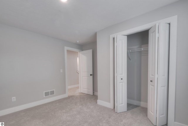 unfurnished bedroom featuring light colored carpet and a closet