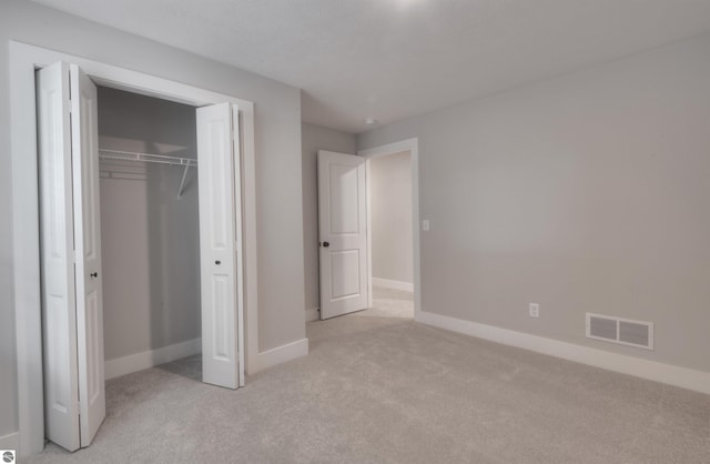 unfurnished bedroom with light colored carpet and a closet