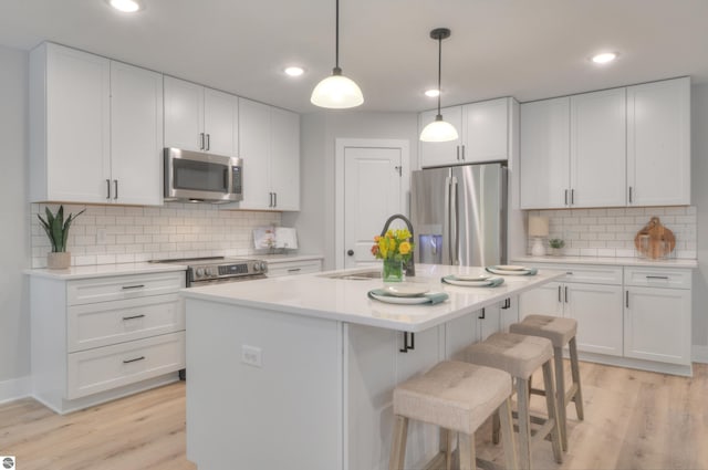 kitchen featuring a kitchen island with sink, white cabinets, and appliances with stainless steel finishes