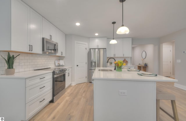 kitchen featuring white cabinetry, light hardwood / wood-style flooring, an island with sink, and stainless steel appliances