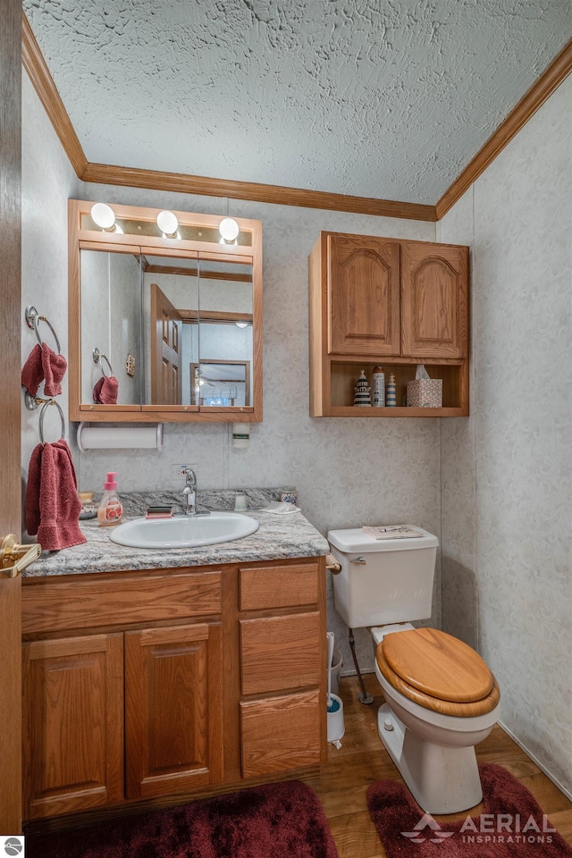 bathroom with ornamental molding, vanity, a textured ceiling, wood-type flooring, and toilet