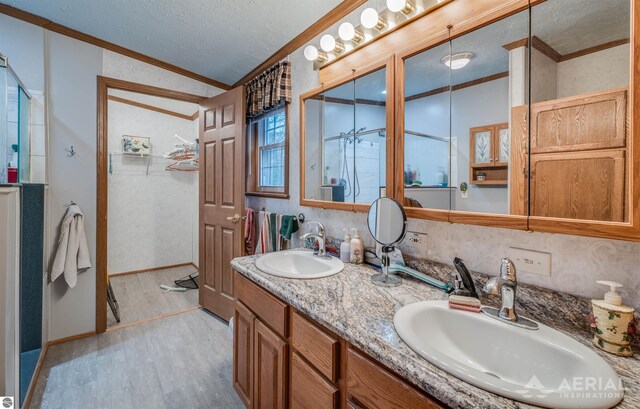 bathroom featuring a textured ceiling, vanity, wood-type flooring, and ornamental molding