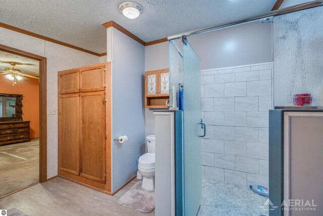 bathroom with a shower with door, crown molding, ceiling fan, toilet, and a textured ceiling