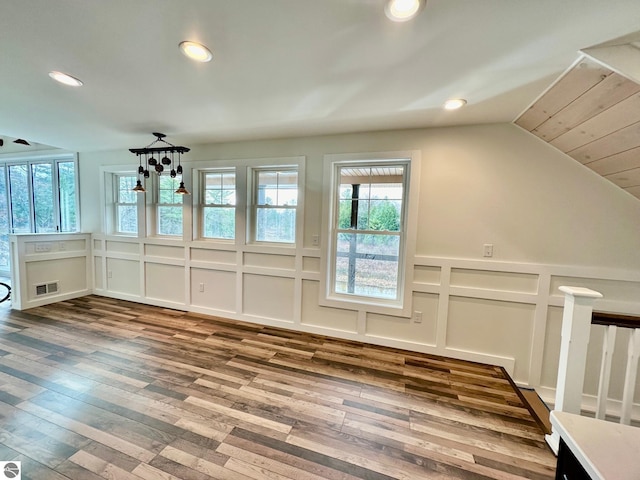 additional living space with hardwood / wood-style floors and vaulted ceiling