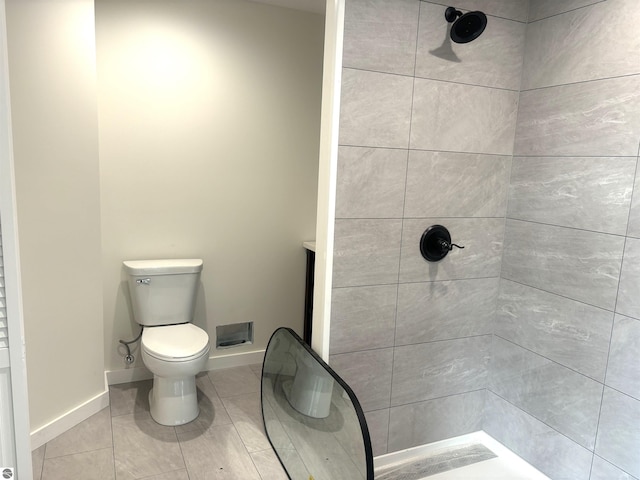 bathroom with tile patterned flooring, toilet, and tiled shower