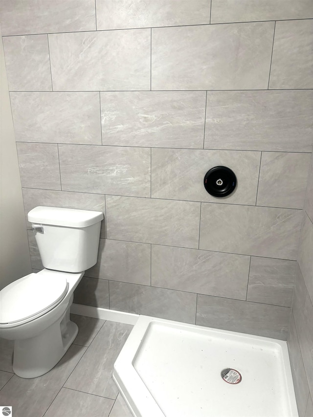 bathroom with a tile shower and toilet