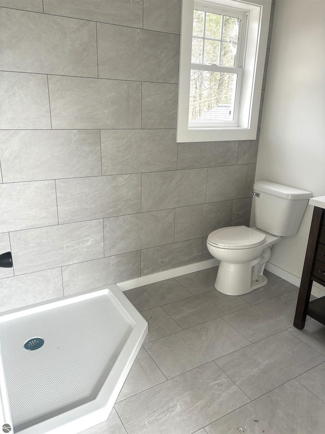 bathroom featuring tile patterned flooring, vanity, toilet, and walk in shower