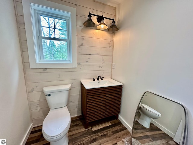 bathroom featuring hardwood / wood-style floors, vanity, toilet, and wooden walls