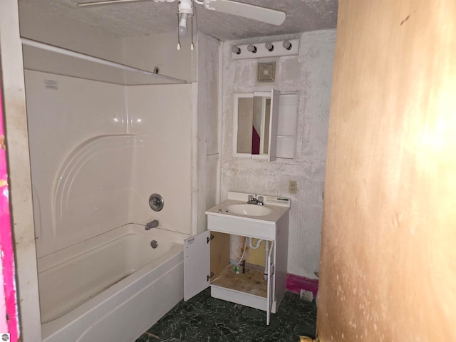 bathroom featuring a textured ceiling, ceiling fan, tub / shower combination, and sink