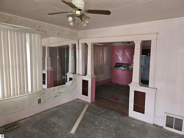 empty room featuring ornate columns, ceiling fan, dark hardwood / wood-style flooring, and wooden walls