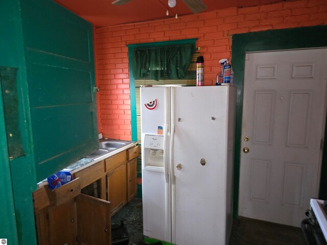 kitchen featuring white fridge with ice dispenser, brick wall, and range