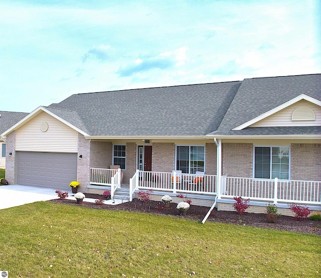 ranch-style home featuring covered porch, a front yard, and a garage