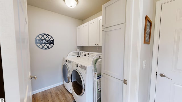 laundry area featuring cabinets, light hardwood / wood-style flooring, and washer and clothes dryer