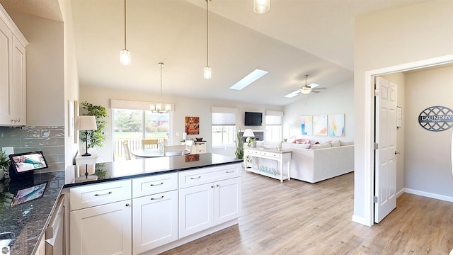 kitchen with white cabinets, ceiling fan with notable chandelier, hanging light fixtures, and light hardwood / wood-style flooring