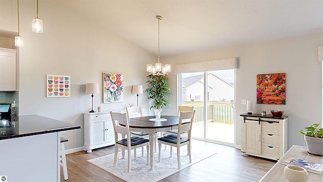 dining area featuring high vaulted ceiling, light hardwood / wood-style flooring, and a notable chandelier