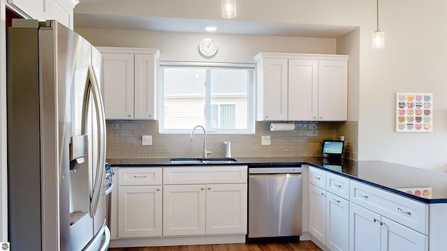 kitchen with white cabinetry, sink, hardwood / wood-style floors, pendant lighting, and appliances with stainless steel finishes