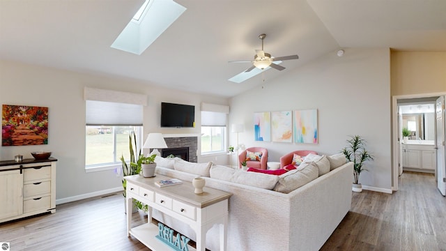 living room featuring a skylight, hardwood / wood-style flooring, high vaulted ceiling, and ceiling fan