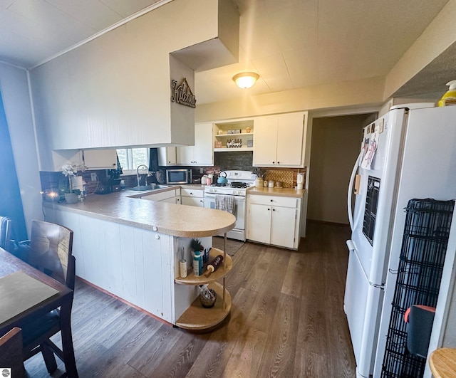 kitchen with white cabinetry, sink, decorative backsplash, kitchen peninsula, and white appliances