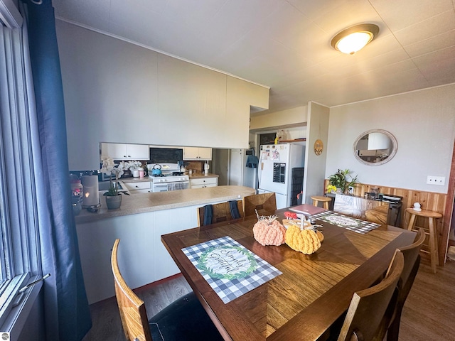 dining space with dark hardwood / wood-style floors and wooden walls