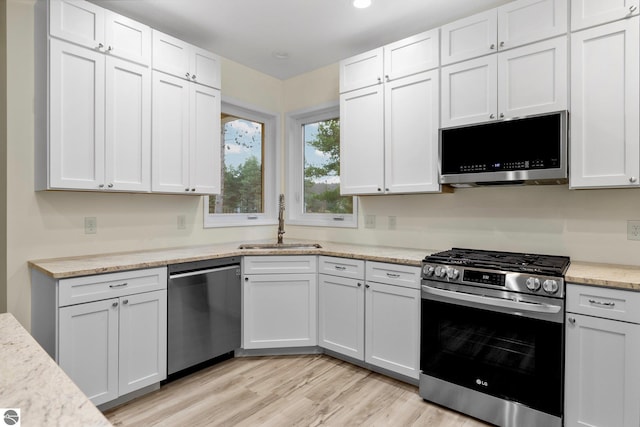 kitchen with sink, white cabinets, light hardwood / wood-style floors, and appliances with stainless steel finishes