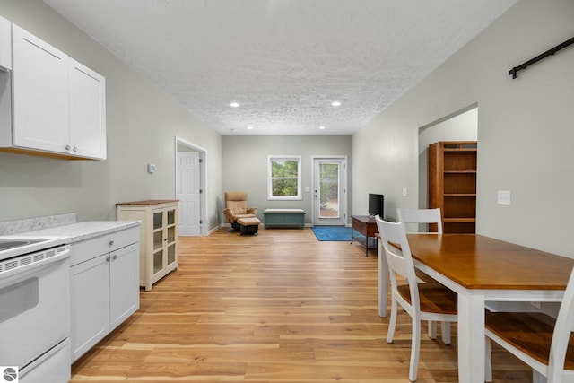 kitchen featuring a textured ceiling, light hardwood / wood-style floors, white cabinetry, and white electric stove