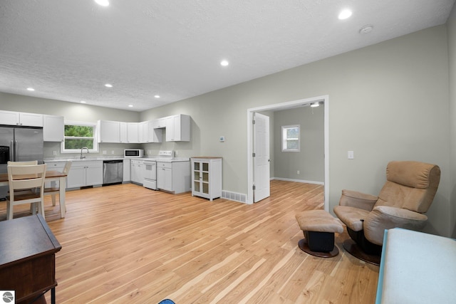 living room featuring a textured ceiling, light wood-type flooring, and sink