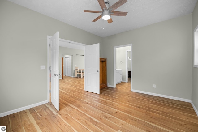 unfurnished bedroom with a textured ceiling, light wood-type flooring, ensuite bath, and ceiling fan