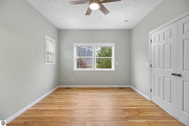 unfurnished room featuring ceiling fan, light wood-type flooring, and a textured ceiling