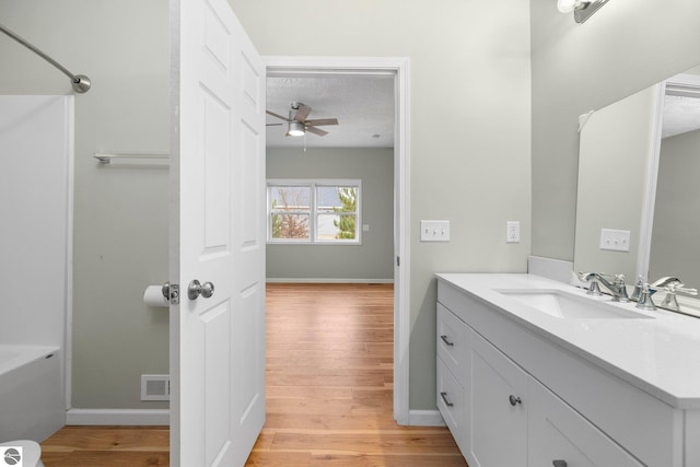 bathroom featuring ceiling fan, hardwood / wood-style floors, vanity, and a textured ceiling