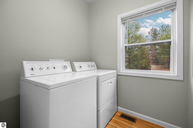 washroom featuring washer and dryer, light hardwood / wood-style flooring, and plenty of natural light