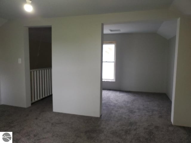 bonus room with dark carpet and lofted ceiling