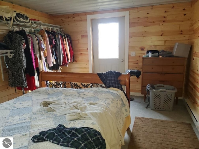 bedroom with wood walls, a baseboard radiator, and a closet