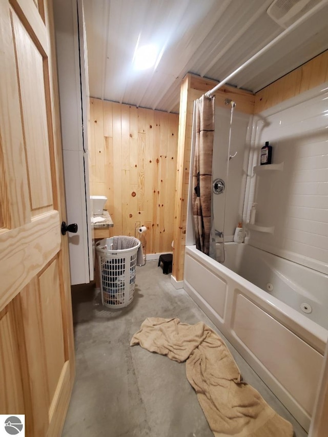 bathroom with concrete floors, shower / tub combo with curtain, and wood walls