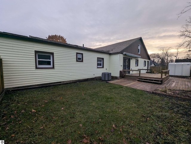 back house at dusk featuring central AC, a yard, and a deck