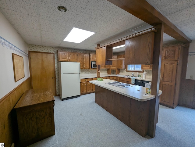 kitchen featuring kitchen peninsula, a paneled ceiling, stainless steel appliances, light colored carpet, and sink