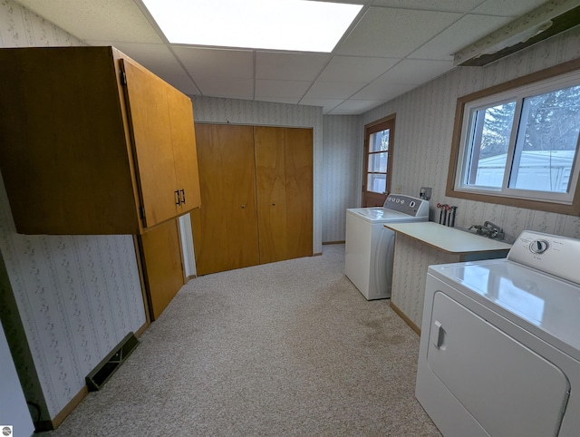 clothes washing area featuring light carpet, cabinets, and independent washer and dryer