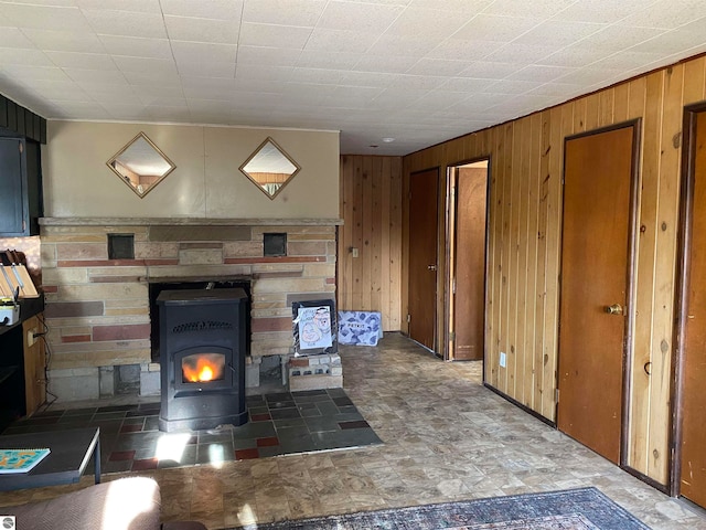 unfurnished living room featuring a wood stove and wood walls