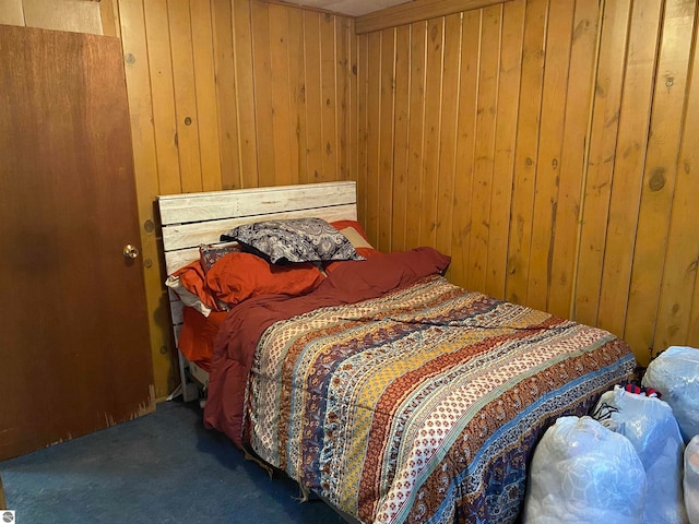 carpeted bedroom featuring wooden walls