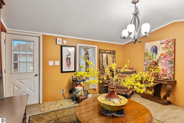 dining space featuring a chandelier, ornamental molding, hardwood / wood-style flooring, and lofted ceiling