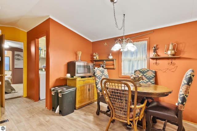 dining space with an inviting chandelier, crown molding, vaulted ceiling, light hardwood / wood-style flooring, and washer / dryer