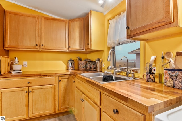 kitchen featuring sink, light wood-type flooring, lofted ceiling, and wood counters