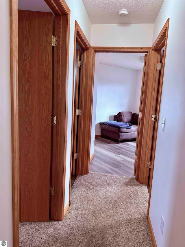 hall with light carpet and a textured ceiling