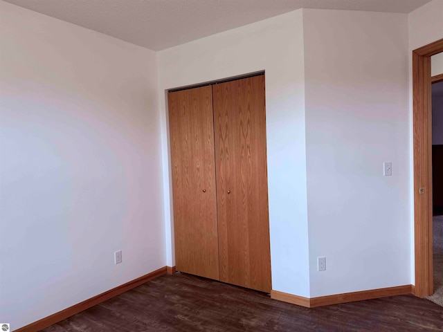 unfurnished bedroom with a closet and dark wood-type flooring