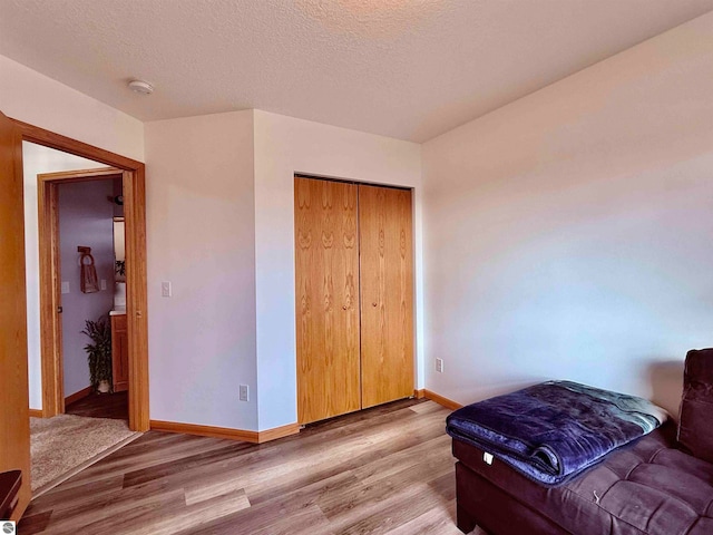 bedroom featuring a closet, light hardwood / wood-style floors, and a textured ceiling