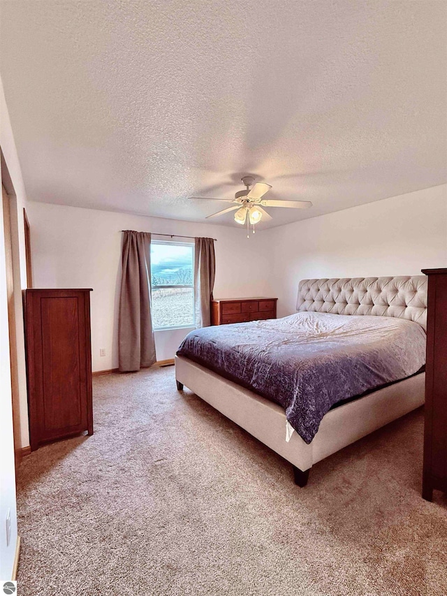 carpeted bedroom featuring a textured ceiling and ceiling fan