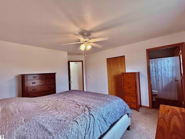 bedroom featuring ceiling fan, light colored carpet, a textured ceiling, and connected bathroom