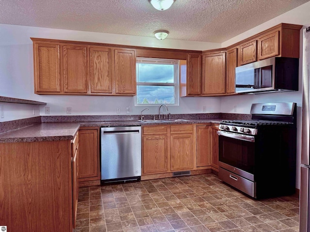 kitchen featuring appliances with stainless steel finishes, a textured ceiling, and sink