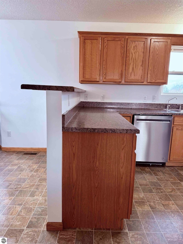 kitchen featuring a textured ceiling, stainless steel dishwasher, and sink