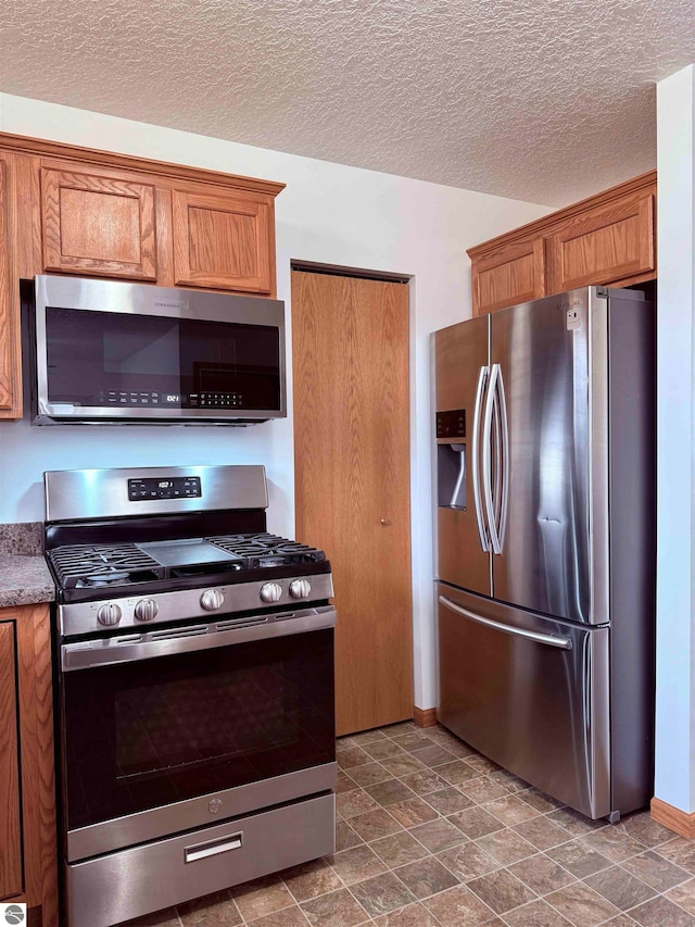 kitchen with a textured ceiling and appliances with stainless steel finishes