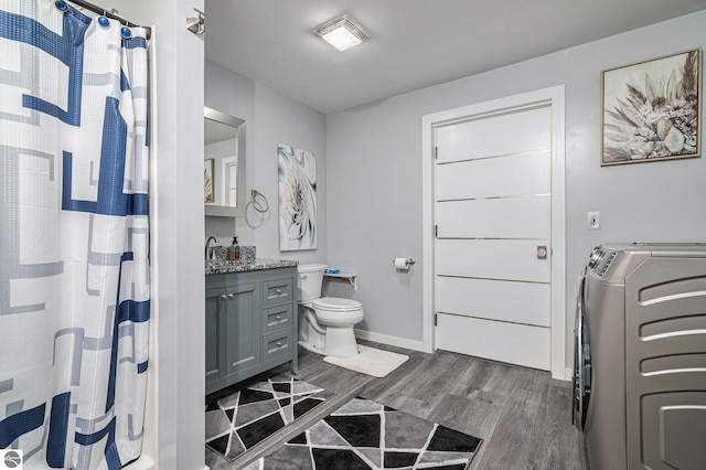 bathroom with hardwood / wood-style floors, vanity, washer and dryer, and toilet